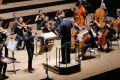 Ein Jugendlicher spielt Trompete mit einem kleinen Orchester