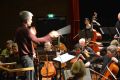 Ein Dirigent leitet das Erwachsenenorchster der Musikschule