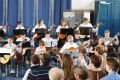 Ein Gitarrenorchester spielt vor einem blauen Vorhang
