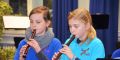 Zwei Mädchen in blauen Pullovern spielen Blockflöte