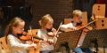 Zwei Mädchen und ein Junge spielen Geige im Orchester