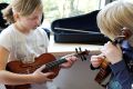 Zwei Kinder zupfen auf der Geige